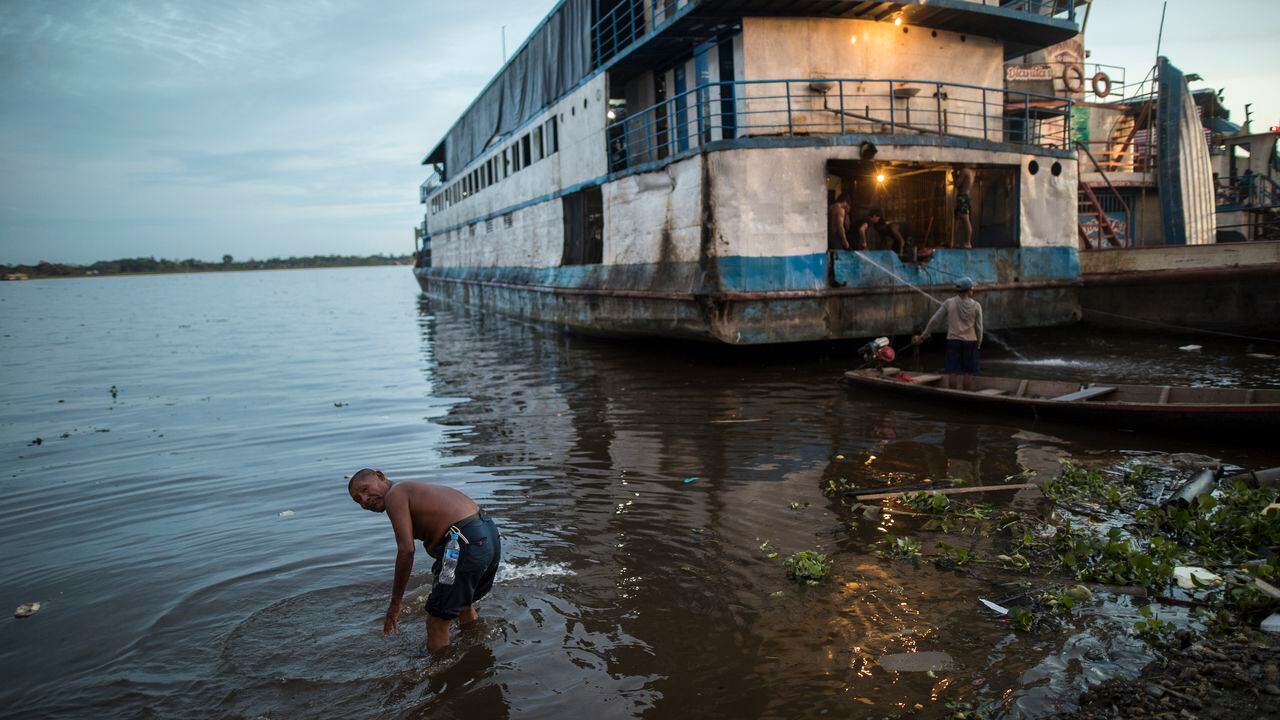 Un hombre se baña en las aguas poco profundas del puerto de Masusa en Iquitos, Perú. (Foto AP / Rodrigo Abd)