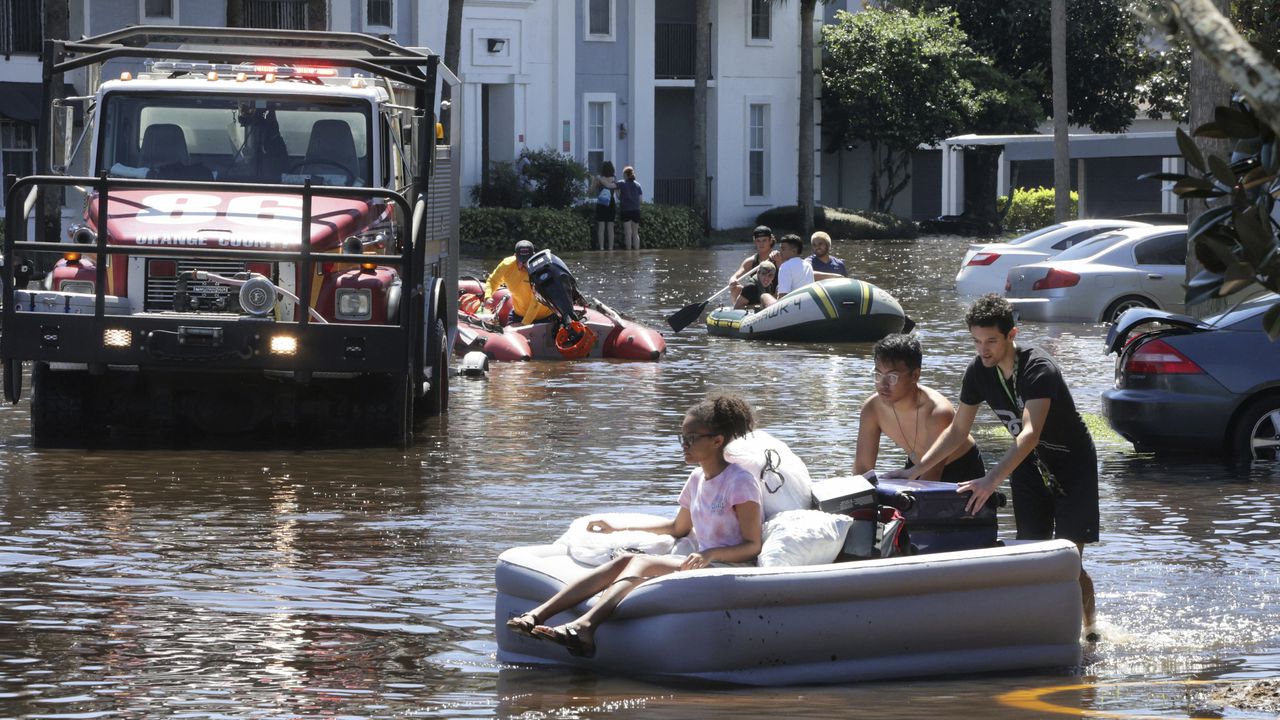 Estudiantes de la Universidad Central de Florida usan un colchón inflable para evacuar un complejo de apartamentos que quedó inundado por la lluvia del huracán Ian. (Joe Burbank/Orlando Sentinel vía AP)