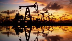 Pump jack silhouette against a sunset sky with reflections in the water.