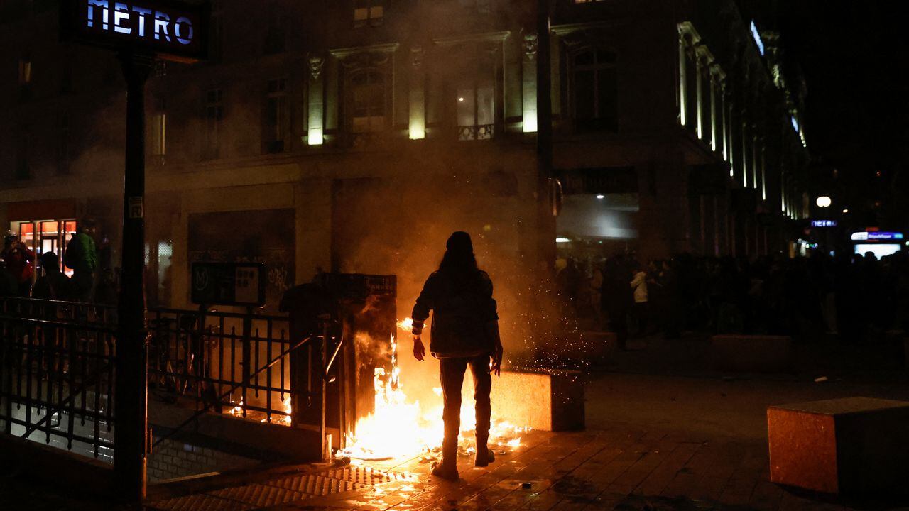 Un manifestante camina junto a un fuego durante una manifestación, un día después de que se adoptara la reforma de las pensiones cuando el Parlamento francés rechazó dos mociones de censura contra el gobierno, en la Place de la Republique en París