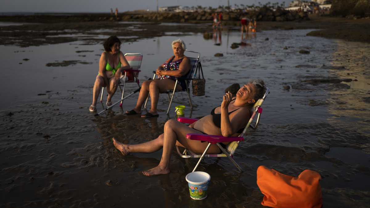 Personas toman el sol en una playa en Chipiona, ubicado en la costa del Atlántico, en la provincia Cadiz, España, el viernes 9 de julio de 2021. (AP Foto/Emilio Morenatti)