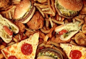 Concepto de comida rápida con restaurante frito grasiento para llevar como hamburguesa de aros de cebolla y perros calientes con papas fritas de pollo frito y pizza como símbolo de la tentación de la dieta que resulta en una nutrición poco saludable.