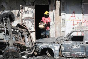 Un hombre con un casco de bombero prestado saca sus pertenencias de un edificio después de que un camión de combustible explotara y matara a decenas de personas en medio de informes de que residentes cercanos habían intentado sacar combustible del vehículo antes de que explotara, en Cap Haitien, Haití, el 15 de diciembre de 2021. Foto REUTERS / Ralph Tedy Erol
