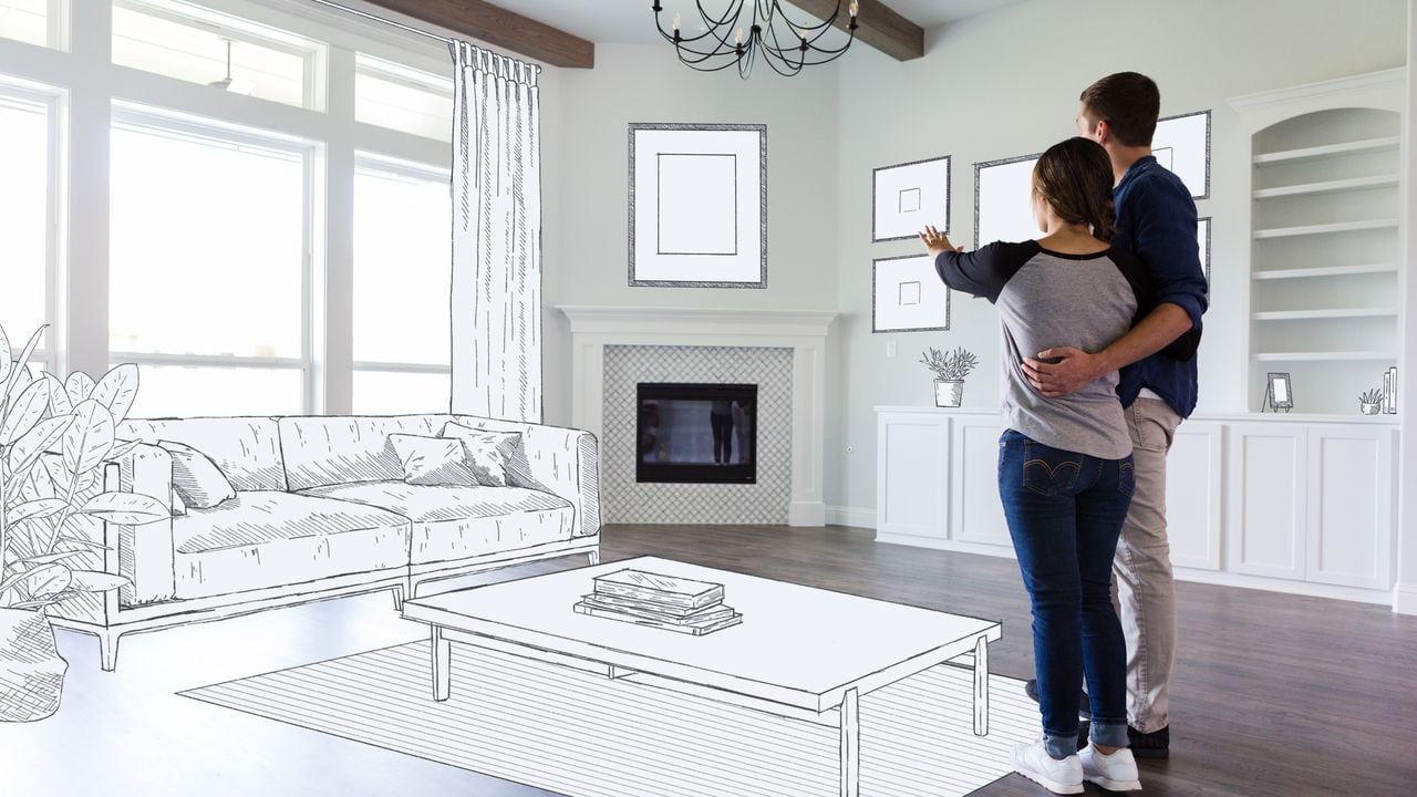 Una pareja joven se para en la sala de estar vacía de su nuevo hogar e imagina la decoración de la habitación y la ubicación de los muebles. Sala imaginaria