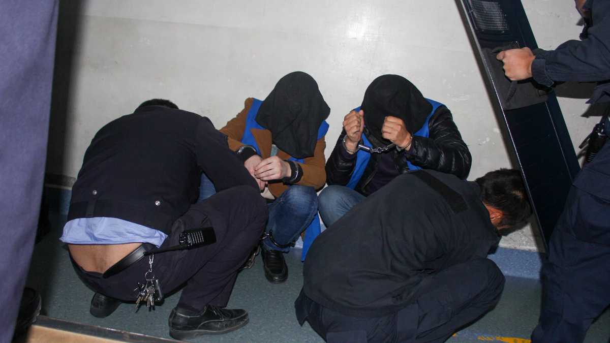 Una de las fotos muestra a dos detenidos encapuchados y acurrucados ante las fuerzas de seguridad chinas.