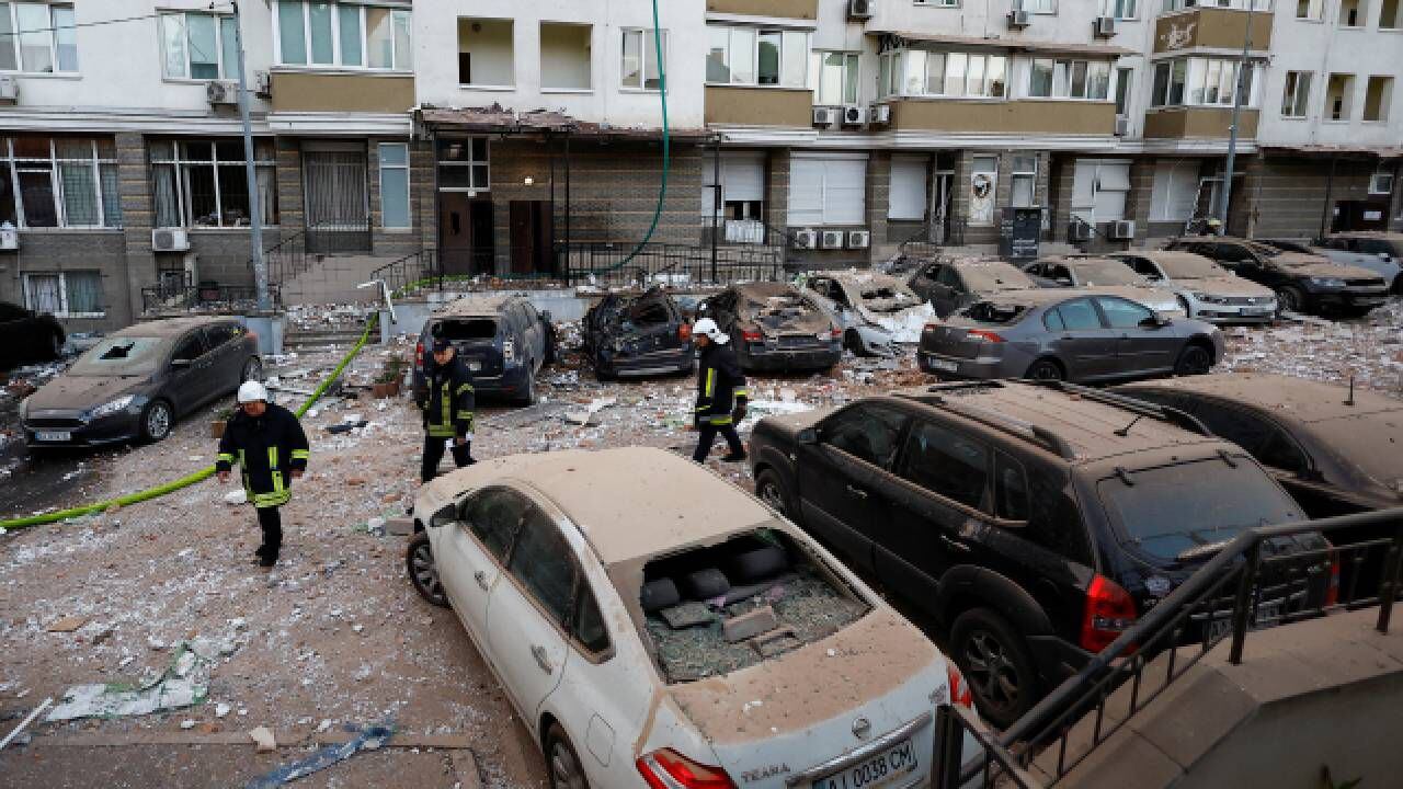 Los bomberos caminan cerca de los automóviles dañados durante un ataque masivo con aviones no tripulados.