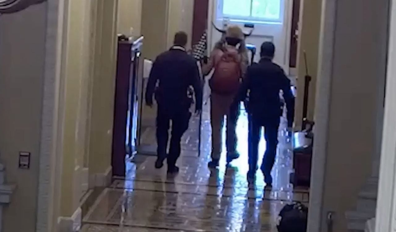 QAnon Shaman acompañado de dos policías dentro del Capitolio de Estados Unidos