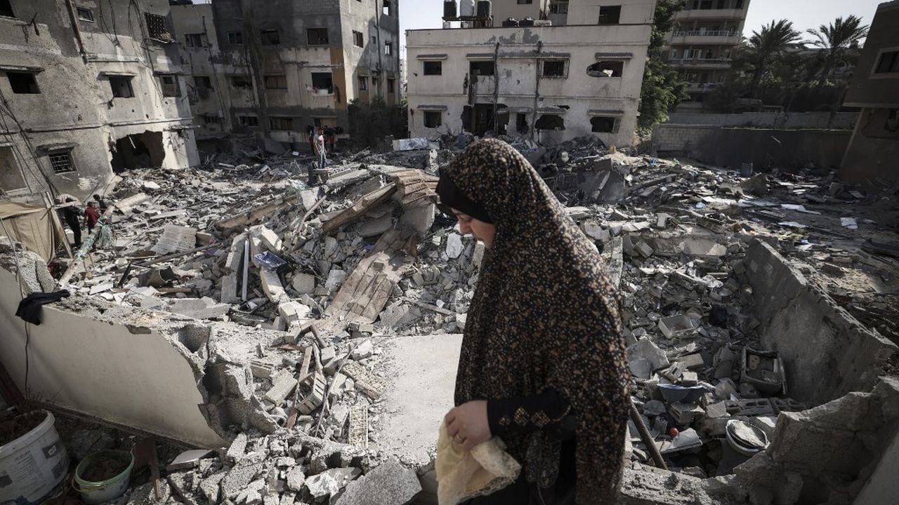 Una mujer palestina revisa los daños mientras camina entre los escombros frente a su casa en la ciudad de Gaza a principios del 8 de agosto de 2022, luego de un alto el fuego entre Israel y los militantes palestinos (Foto de Mahmud JAMONES / AFP)