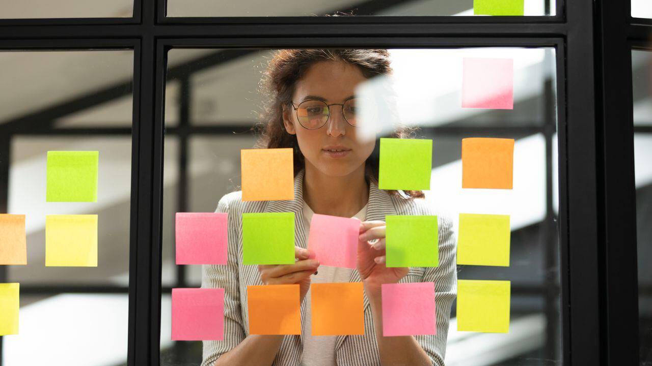 Mujer empresaria creando una lista de tareas con notas adhesivas multicolores