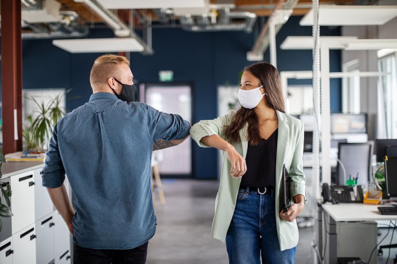 Dos compañeros de trabajo saludando con el codo en la oficina. La gente de negocios se golpea los codos en la oficina para saludar durante la pandemia del covid-19.