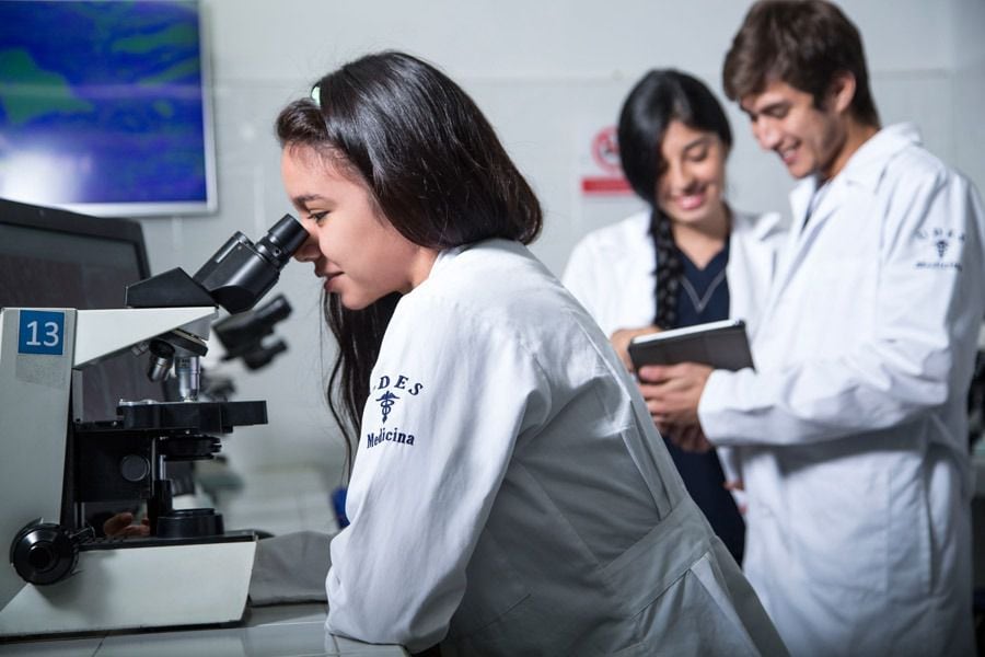Estudiantes de medicina de la UDES en un laboratorio mirando por un microscopio.