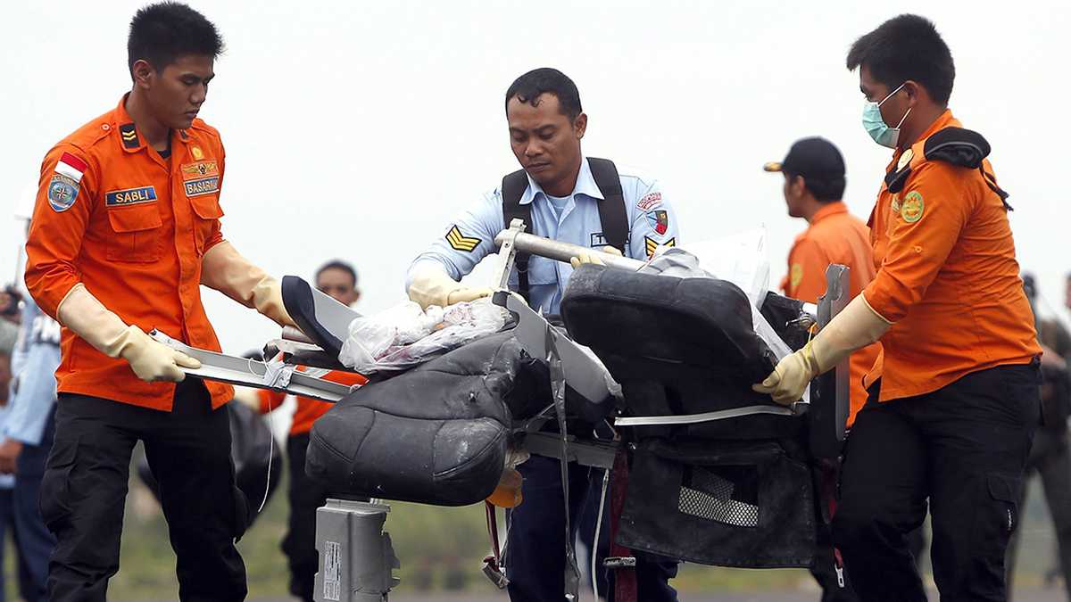 Miembros de la Fuerza Aérea de Indonesia trasladan los restos de un asiento de pasajeros del avión de AirAsia.