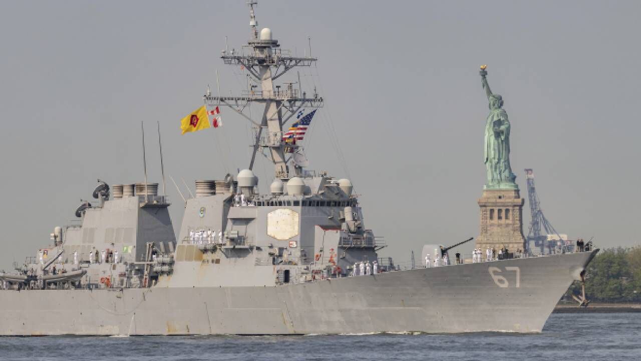 Marineros e infantes de marina estadounidenses se paran en la cubierta del USS Cole, un destructor de misiles guiados, mientras pasa por la Estatua de la Libertad durante la Semana de la flota el miércoles 24 de mayo de 2023 en Nueva York.