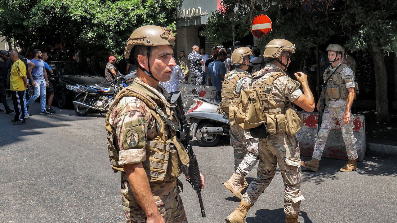 Soldados del ejército (frente) y fuerzas de seguridad (detrás) se reúnen frente a una sucursal del "Banco Federal" en la capital del Líbano, Beirut, el 11 de agosto de 2022. - Un cliente armado con un rifle y que amenazaba con prenderse fuego tomó como rehenes a trabajadores bancarios el 11 de agosto en La capital del Líbano exigió retirar sus ahorros de más de $ 200,000, dijeron fuentes de seguridad. El incidente es el más reciente entre los bancos locales y los depositantes enojados que no pueden acceder a sus ahorros después del colapso económico del Líbano debido a los controles de capital informales. Un corresponsal de AFP vio a las fuerzas de seguridad rodeando una sucursal cerca de la concurrida calle comercial Hamra en el oeste de Beirut. (Foto de anwar amro / AFP)