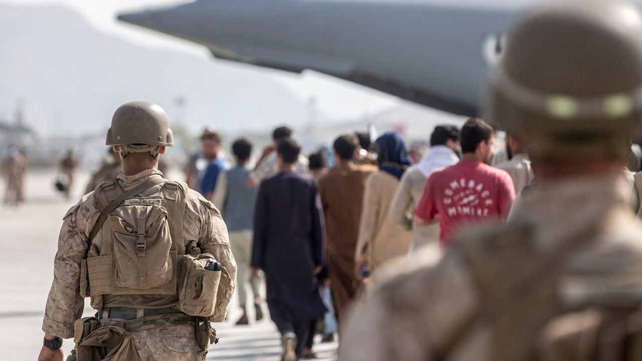 Los infantes de marina con propósito especial de la Fuerza de Tarea Marítima Aire-Tierra-Respuesta a Crisis-Comando Central (SPMAGTF-CR-CC) guían a los evacuados hacia un Boeing C de la Fuerza Aérea de EE. UU. 17 Globemaster III durante una evacuación en el aeropuerto internacional Hamid Karzai en Kabul, Afganistán. (Sargento Samuel Ruiz / Cuerpo de Marines de EE. UU. A través de AP)