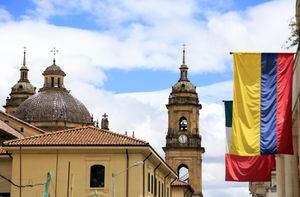 The view of the dome and bell towers of Primatial Cathedral of Bogota (Metropolitan Cathedral Basilica of the Immaculate Conception) in La Candelaria the historical center of Bogota with Colombian flag in foreground. Bogota.Colombia. 05/2017