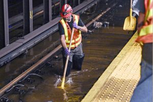 Esta fotografía proporcionada por el servicio MTA New York City Transit, muestra a un trabajador metido en las vías inundadas de la estación de metro de Times Square, en Nueva York, el martes 29 de agosto de 2023. (Marc A. Hermann / MTA, via AP)