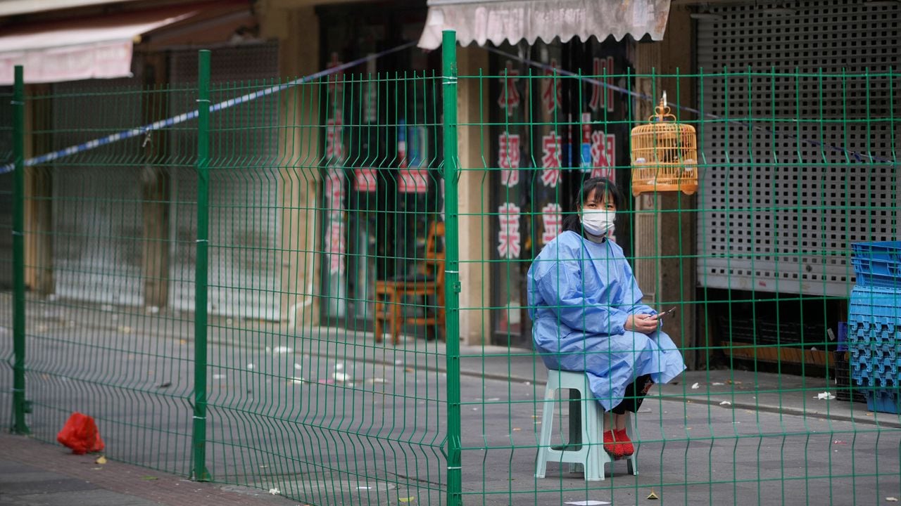 Un trabajador con traje de protección se sienta detrás de una barrera en una zona sellada tras el brote de la enfermedad por coronavirus (COVID-19), en Shanghái, China, el 11 de octubre de 2022. REUTERS/Aly Song