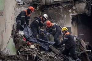 Los equipos de rescate transfieren el cuerpo de un hombre muerto en un ataque con misiles rusos en un edificio de apartamentos a una bolsa de plástico en la ciudad de Dnipro, en el sureste de Ucrania, el lunes 16 de enero de 2023. (AP Photo/Evgeniy Maloletka)