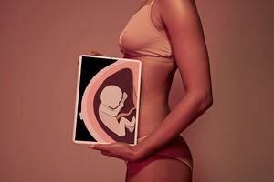 Female holding tablet in front of body to display coloured x-ray illustrations made out of hand made paper structures