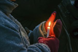 Una mujer protege una vela de la nieve que cae durante la Vigilia de oración por la paz en Ucrania y el mundo el jueves 10 de marzo de 2022 por la noche. (Amanda Haverstick/The News Dispatch via AP)