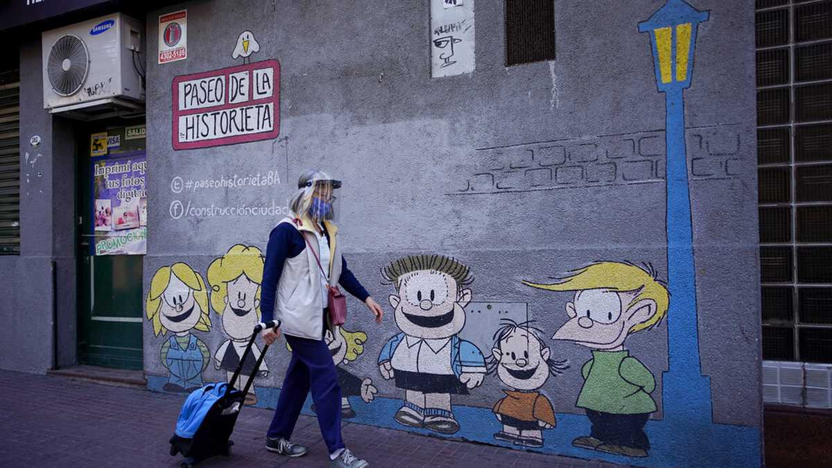 A woman past a mural featuring characters from the comic strip character Mafalda created by Argentine cartoonist Joaquin Salvador Lavado, who was better known as Quino, in Buenos Aires, Argentina, Wednesday, Sept. 30, 2020. Lavado passed away on Wednesday, according to his editor Daniel Divinsky who announced it on social media. He was 88. (AP Photo/Victor R. Caivano)