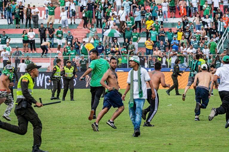 This handout picture released by Cortulua's Press Office shows fans of Colombia's Deportivo Cali invade the field and try to attack players and staff members of their team during the Colombian league football match between Cortulua and Deportivo Cali in Tula, Colombia, on September 21, 2022. (Photo by Cortulua's Press Office / AFP) / RESTRICTED TO EDITORIAL USE - MANDATORY CREDIT "AFP PHOTO / CORTULUA'S PRESS OFFICE" - NO MARKETING NO ADVERTISING CAMPAIGNS - DISTRIBUTED AS A SERVICE TO CLIENTS