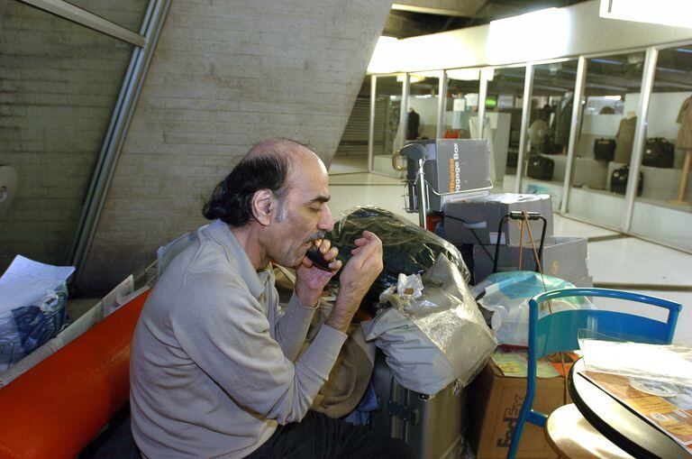 En esta foto de archivo tomada el 12 de agosto de 2004, Mehran Karimi Nasseri se afeita, temprano en la mañana, en la terminal 1 del aeropuerto Charles De Gaulle de París. - Mehran Karimi Nasseri, un refugiado político que vivió más de 18 años en el aeropuerto Roissy-Charles de Gaulle de París e inspiró "La terminal" del director Steven Spielberg, murió, a los 77 años, en la terminal 2F del aeropuerto Roissy-Charles de Gaulle, según informó a AFP por funcionarios del aeropuerto. (Foto de STEPHANE DE SAKUTIN / AFP)