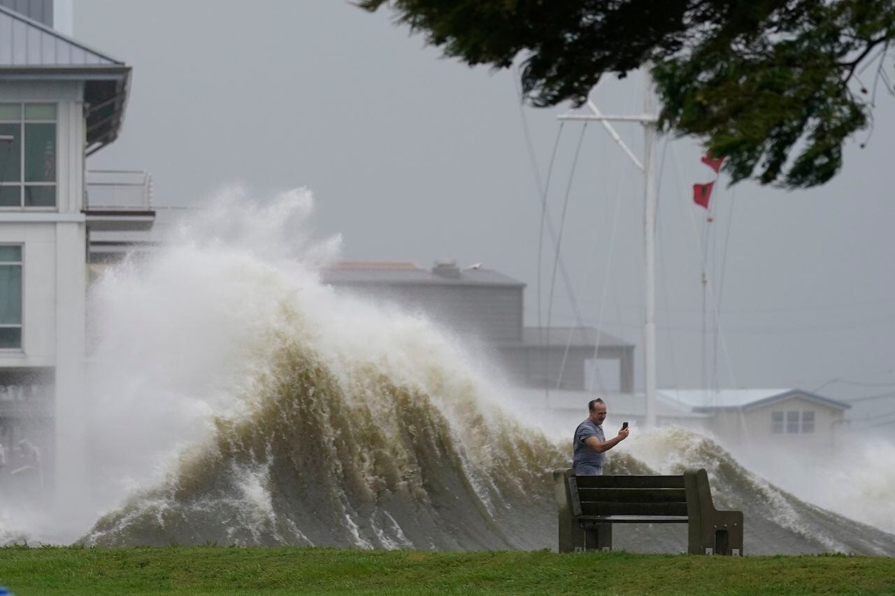 Esta fotografía muestra a un hombre que toma fotografías frente a grandes olas en la orilla del lago Pontchartrain, en Nueva Orleans, el domingo 29 de agosto de 2021. (AP Foto/Gerald Herbert)