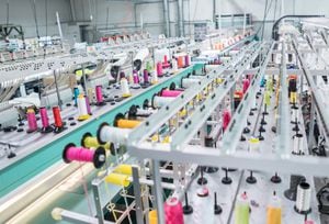 Máquina de bordar en funcionamiento en una fábrica de ropa - conceptos de la industria de la moda