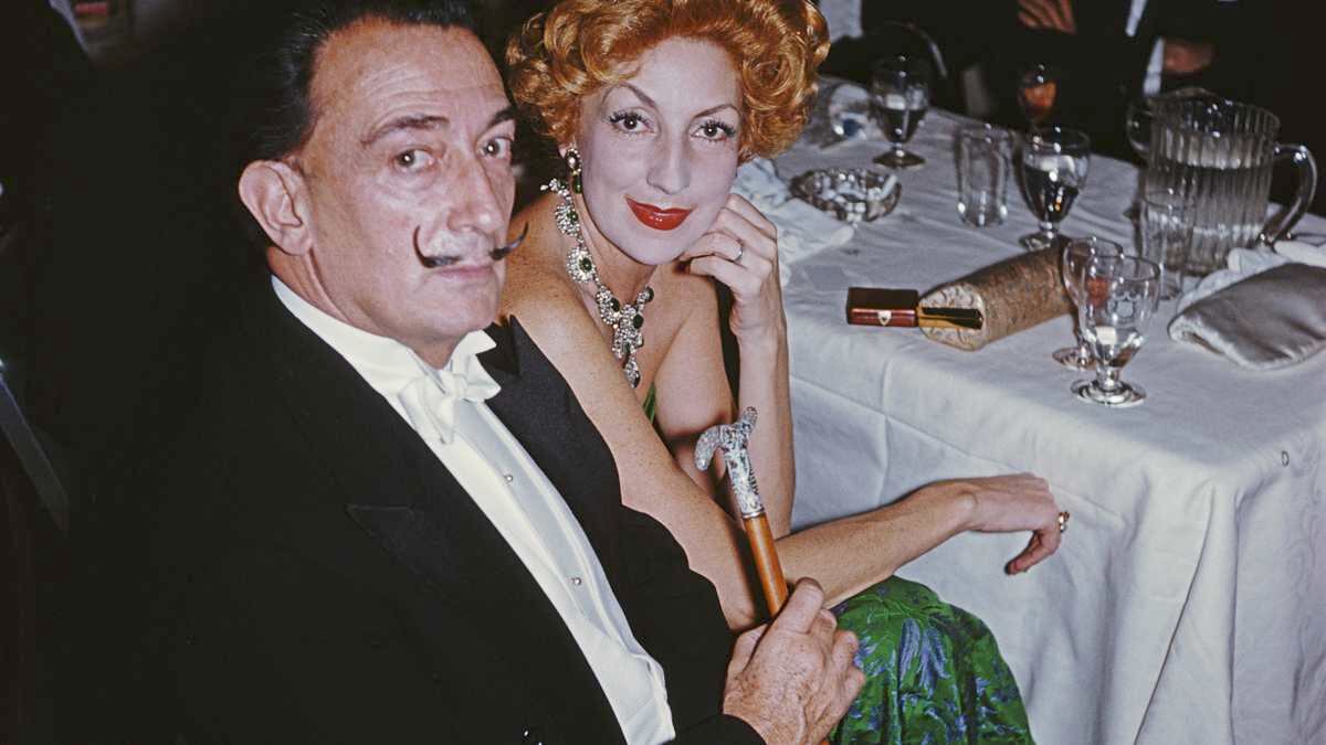 circa 1959:  Surrealist painter Salvador Dali (1904 - 1989) with a red-haired woman at a ball in New York.  A Wonderful Time - Slim Aarons  (Photo by Slim Aarons/Getty Images)