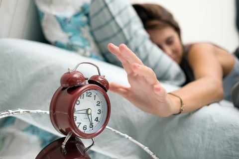 Mujer despertando con reloj despertador