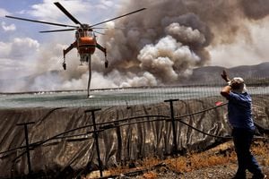 Se está llenando un helicóptero con agua de un tanque mientras un incendio forestal arde cerca del pueblo de Spathovouni, cerca de Corinto, Grecia, el 23 de julio de 2021. Foto: REUTERS / Vassilis Psomas TPX IMÁGENES DEL DÍA