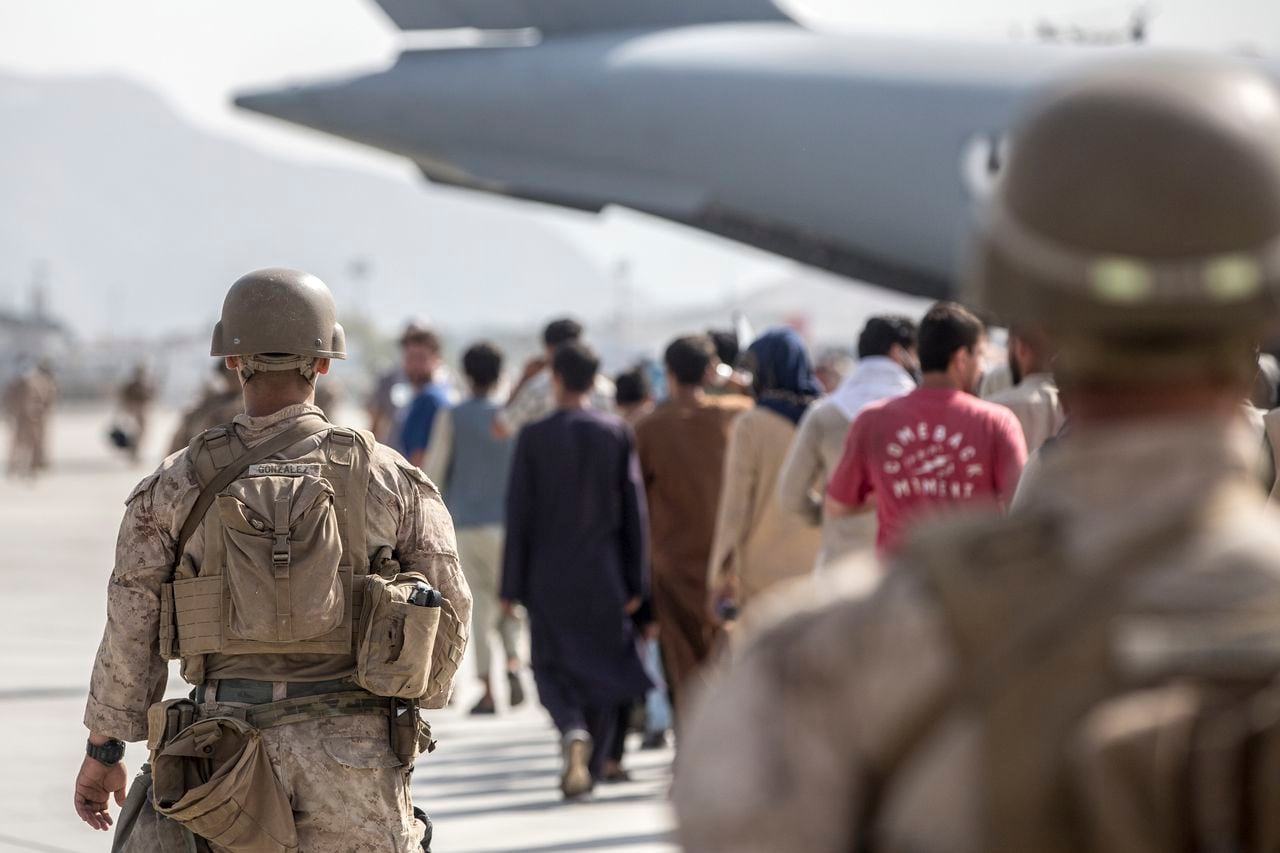 Los infantes de marina con propósito especial de la Fuerza de Tarea Marítima Aire-Tierra-Respuesta a Crisis-Comando Central (SPMAGTF-CR-CC) guían a los evacuados hacia un Boeing C de la Fuerza Aérea de EE. UU. 17 Globemaster III durante una evacuación en el aeropuerto internacional Hamid Karzai en Kabul, Afganistán. (Sargento Samuel Ruiz / Cuerpo de Marines de EE. UU. A través de AP)