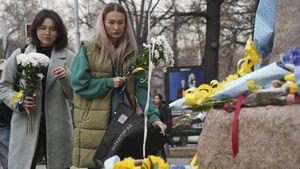 Women arrive to lay flowers with ribbons in the colors of the Ukrainian national flag at the statue of Taras Shevchenko, also known as Kobzar, a Ukrainian poet, writer, artist, public and political figure, to mark the first anniversary of Russia's full-scale invasion of Ukraine in Almaty, Kazakhstan, Friday, Feb. 24, 2023. ((Vladimir Tretyakov/NUR.KZ via AP)