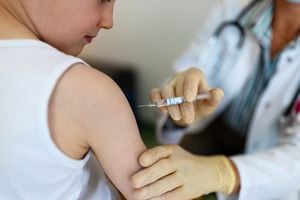 Niño recibiendo una vacuna contra la gripe en la clínica. Niño pequeño recibiendo una vacuna en su brazo por un pediatra con guantes.