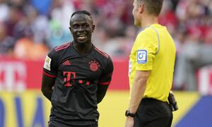 Sadio Mané del Bayern Múnich charla con el árbitro Harm Osmers a la espera de la decisión del VAR en el partido contra Wolfsburgo en la Bundesliga, el domingo 14 de agosto de 2022. (AP/Matthias Schrader)