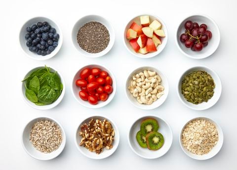 A grouping of various super foods. Blueberries, chia, apples, grapes, spinach, tomatoes, grapes, cashews, pepitas, sunflower seeds, walnuts, kiwi, oatmeal