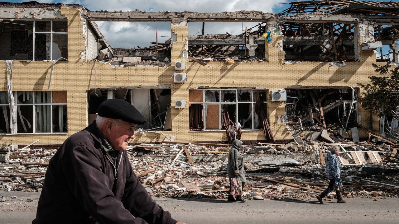 La gente pasa frente a un edificio destruido en Kupiansk, región de Kharkiv, el 19 de septiembre de 2022, en medio de la invasión rusa de Ucrania. - En la ciudad nororiental de Kupiansk, que fue recapturada por las fuerzas ucranianas, continuaron los enfrentamientos con el ejército ruso atrincherado en el lado este del río Oskil. (Foto de Yasuyoshi CHIBA / AFP)