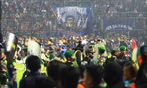 MALANG, INDONESIA - OCTOBER 01: Football supporters enter the pitch as security officers try to disperse them during a riot following a soccer match at Kanjuruhan Stadium in Malang, East Java, Indonesia, 01 October 2022. According to government officials, at least 174 people including police officers were killed mostly in stampedes after riots following a soccer match. (Photo by Getty Images/Suryanto/Anadolu Agency)