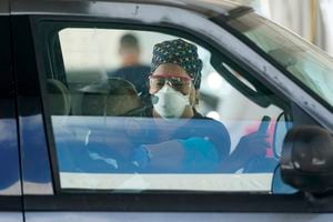 A healthcare worker administers a dose of the Pfizer COVID-19 vaccine to a driver, Wednesday, March 17, 2021, at the Miami-Dade County Tropical Park COVID-19 vaccination site in Miami. (AP Photo/Wilfredo Lee)