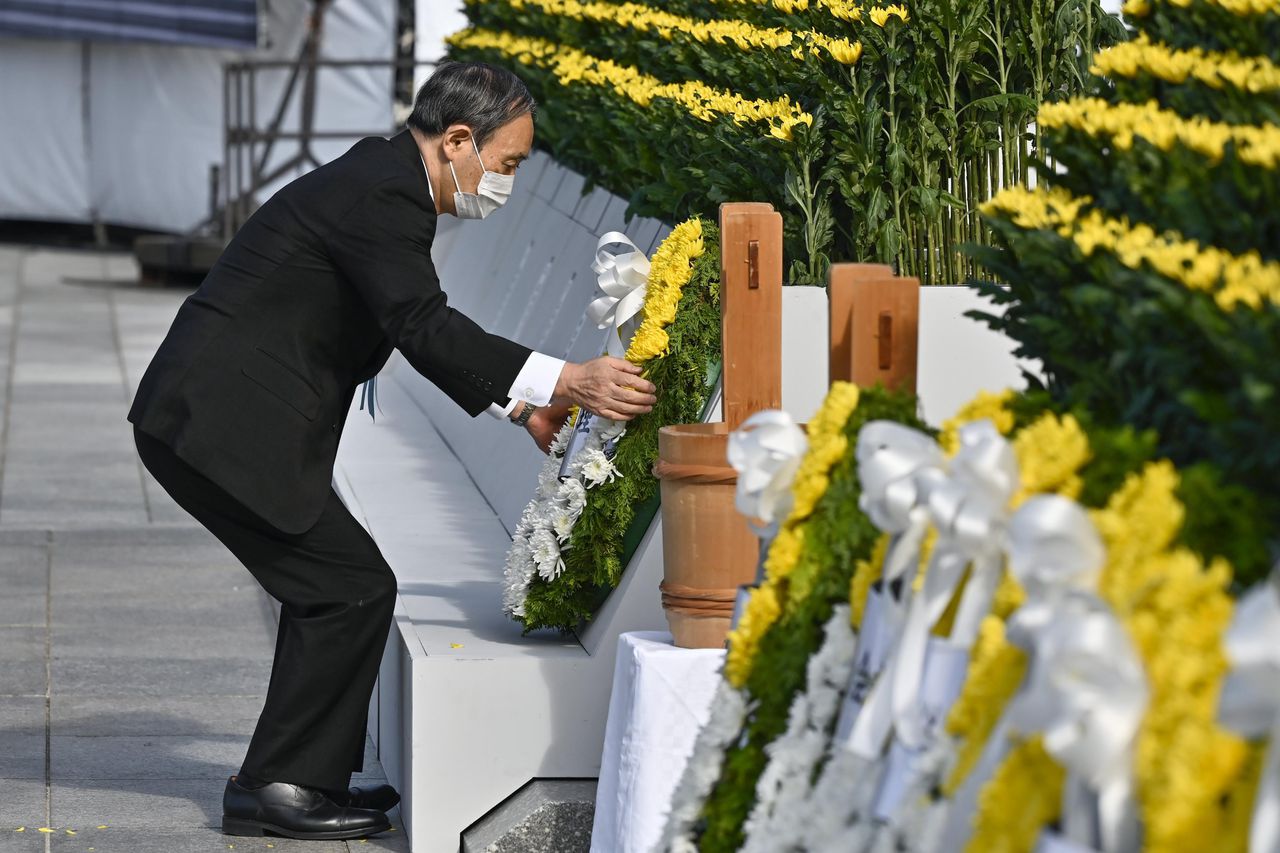 El primer ministro de Japón, Yoshihide Suga, ofrece una ofrenda floral frente al cenotafio dedicado a las víctimas del bombardeo atómico en el Parque Conmemorativo de la Paz de Hiroshima en Hiroshima, en el oeste de Japón. (Kyodo News via AP)