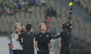 Egypt's head coach Carlos Queiroz, centre, looks up as referee Maguette Ndiaye of Senegal, right, shows a yellow card to one of his team officials during the African Cup of Nations 2022 quarter-final soccer match between Egypt and Morocco at the Ahmadou Ahidjo stadium in Yaounde, Cameroon, Sunday, Jan. 30, 2022. (AP Photo/Themba Hadebe)