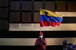 Un partidario del gobernante partido socialista ondea una bandera venezolana al margen de una conferencia de prensa del excanciller Jorge Arreaza, quien concedió la repetición de las elecciones para gobernador del día anterior al candidato opositor Sergio Garrido en Barinas, Venezuela, el lunes 10 de enero de 2022. (AP Photo/Matias Delacroix)