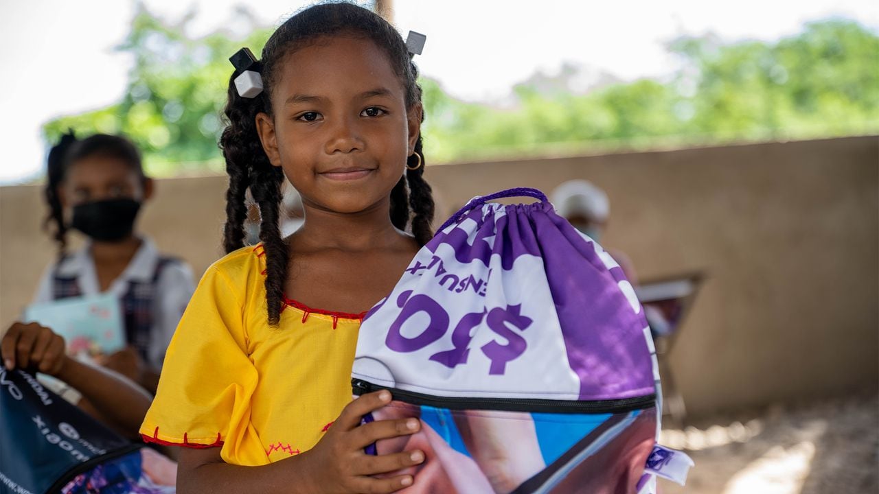 La niña guajira Maité sostiene una tula elaborada con material publicitario de WOM.