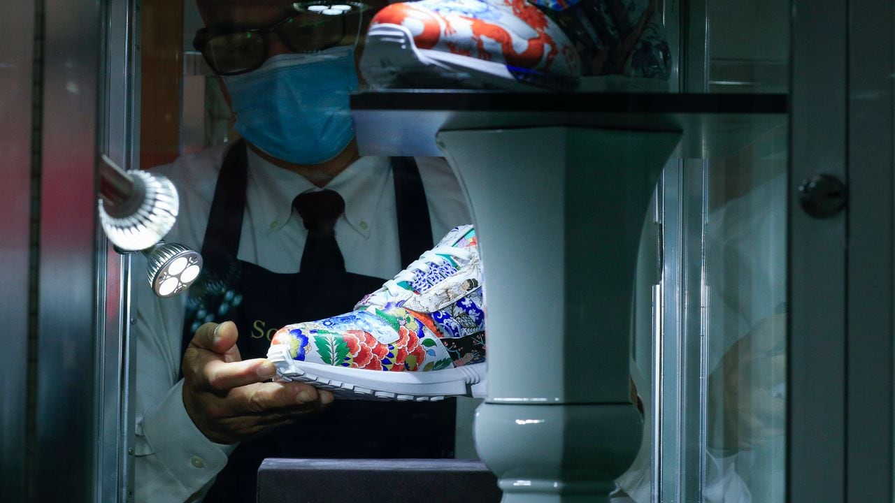 Un manipulador de arte de Sotheby's sostiene unas zapatillas de deporte únicas de Adidas y Meisse llamadas ZX8000 Porcelain, durante una vista previa en la casa de subastas de Sotheby's el 4 de diciembre de 2020 en la ciudad de Nueva York. Las zapatillas podrían alcanzar hasta un millón de dólares en una subasta, según Stheby's.