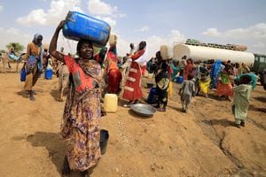 Una refugiada sudanesa, que huyó de la violencia en la región de Darfur en Sudán, lleva un bidón de agua mientras camina hacia su refugio improvisado cerca de la frontera entre Sudán y Chad en Koufroun, Chad, 10 de mayo de 2023. 