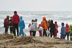 Rescatistas recuperan un cadáver de una playa cercana a Cutro, en el sur de Italia, el domingo 26 de febrero de 2023, después de que un bote de migrantes se partiera en un mar picado.