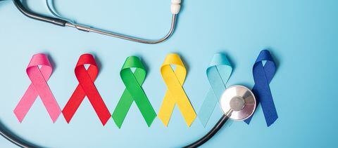 Día mundial del cáncer (4 de febrero). cintas de colores de conciencia; color azul, rojo, verde, rosa y amarillo sobre fondo de madera para apoyar a las personas que viven y enferman. Concepto de salud y medicina