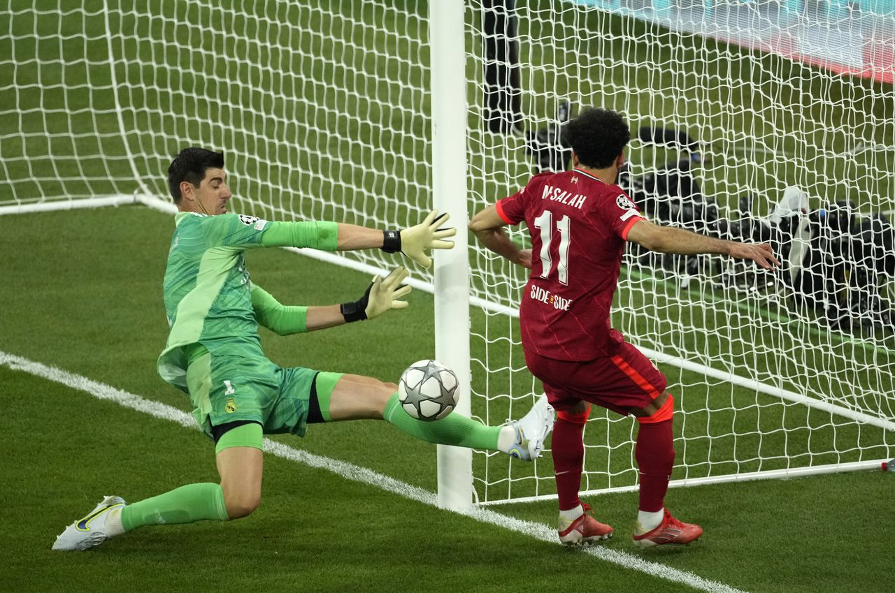 Real Madrid's goalkeeper Thibaut Courtois, left, makes a save in front of Liverpool's Mohamed Salah during the Champions League final soccer match between Liverpool and Real Madrid at the Stade de France in Saint Denis near Paris, Saturday, May 28, 2022. (AP Photo/Christophe Ena)